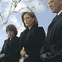 Scullys mother stands to her right. Skinner to her left.